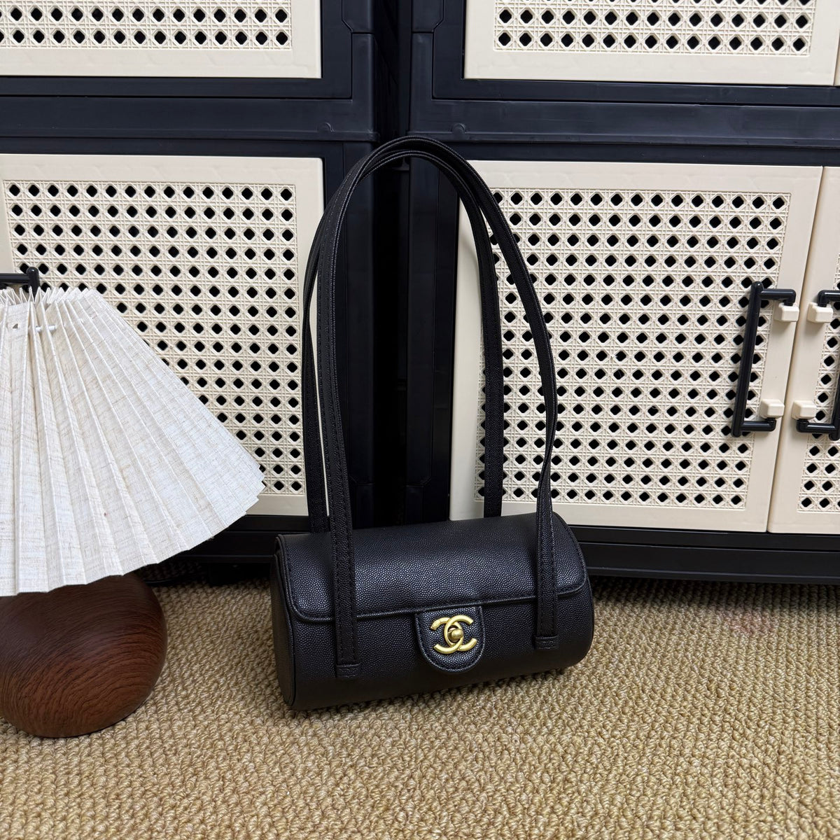 Black caviar leather barrel bag with gold clasp, angled view