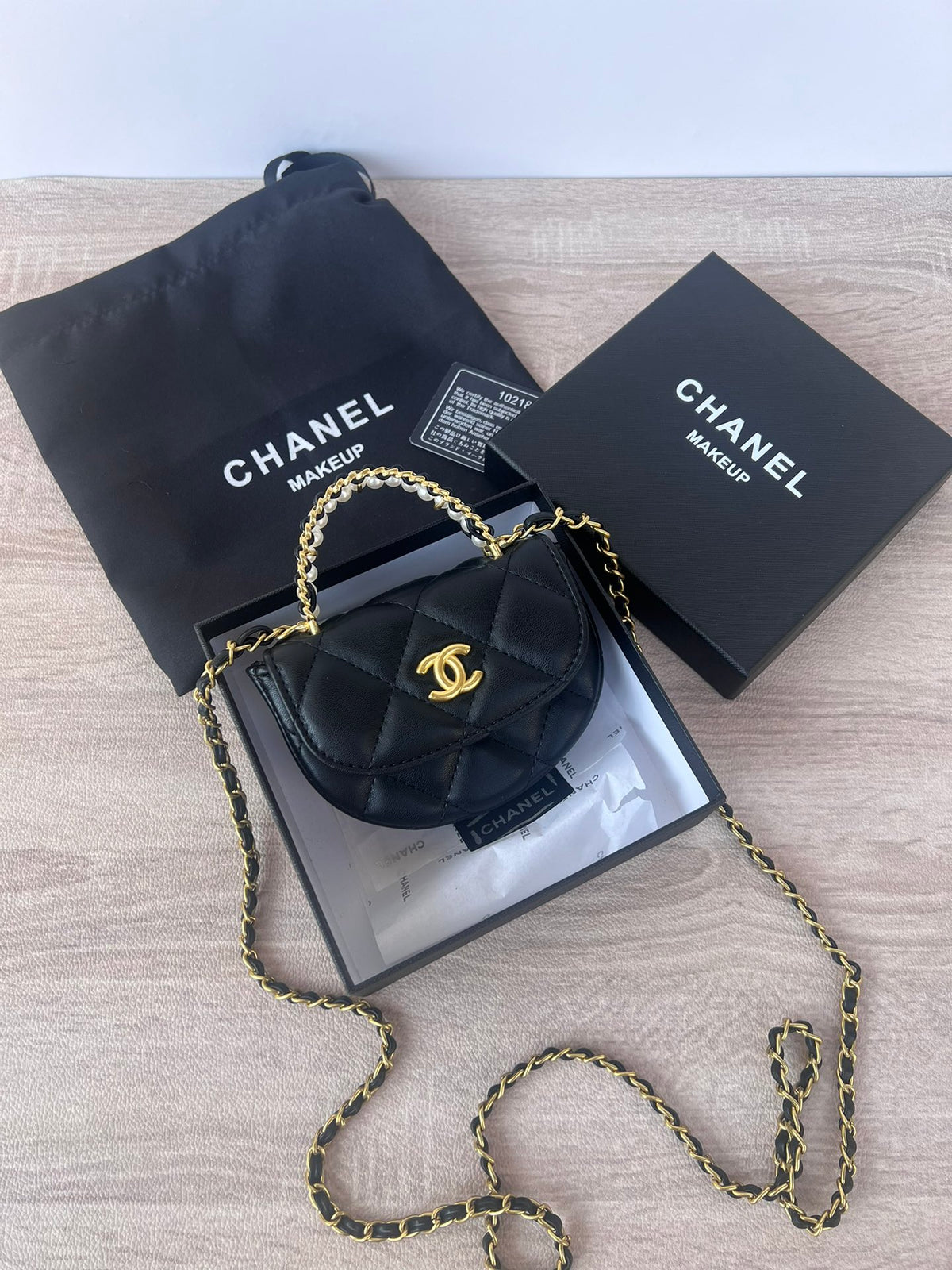 Black pearl chain mini bag with gold hardware and pearl-and-leather woven top handle, front view