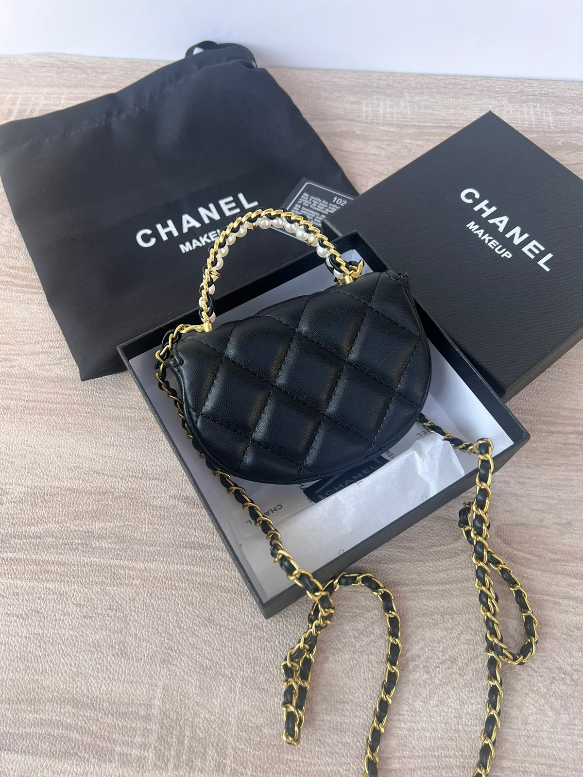 Black mini bag with pearl chain strap, side view